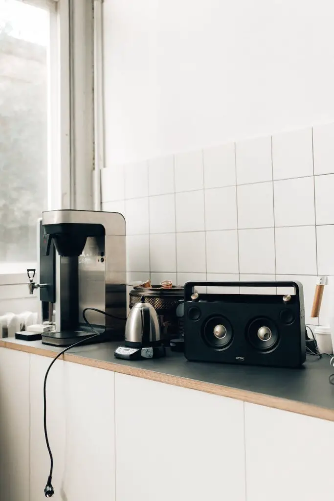 black and silver coffee maker beside white ceramic wall tiles