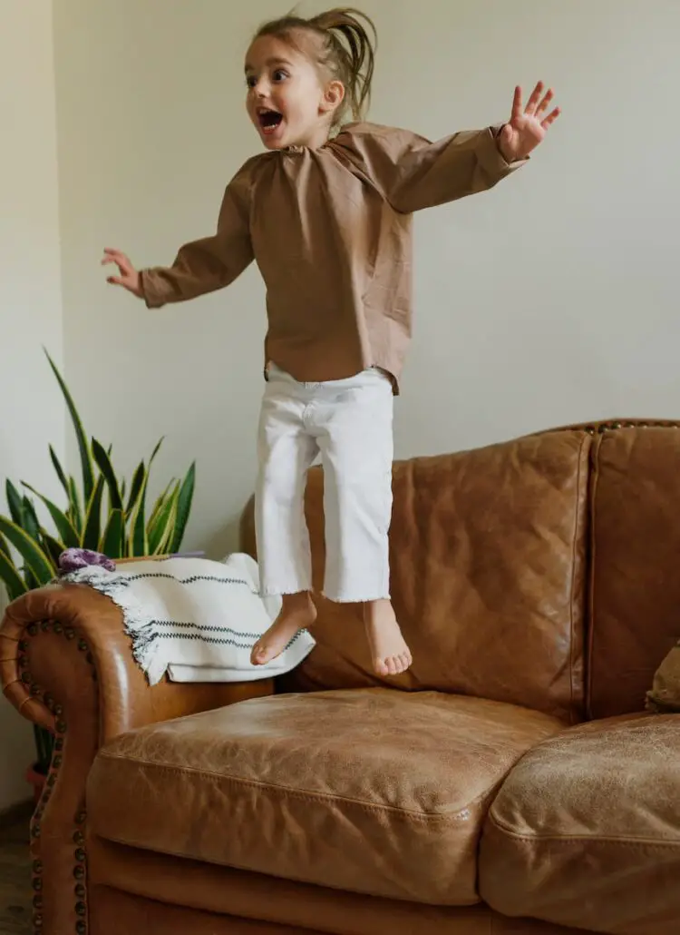 excited girl jumping on couch in living room