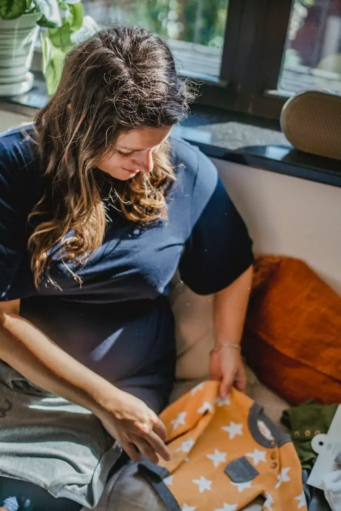 smiling woman carefully packing clothes for unborn child